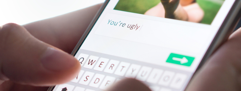 Image of hands commenting on someone's picture "You're uugly" on their smartphones and are about the send the message