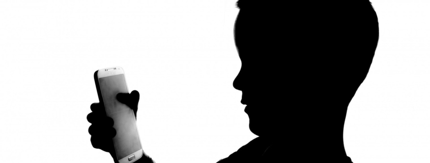 Silhouette of a young boy with a smartphone in his hands