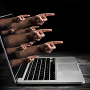 Image of mange hands with pointing index finger coming out of laptop screen.