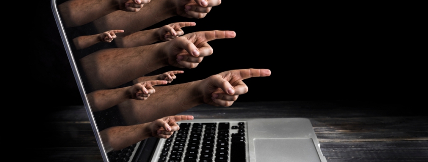 Image of mange hands with pointing index finger coming out of laptop screen.